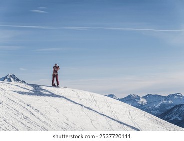 A solitary figure stands atop a snow-covered mountain peak, looking out at the expansive view of distant mountain ranges.  - Powered by Shutterstock