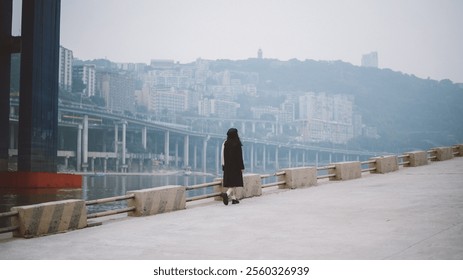 Solitary Figure Walking Along a Riverside Promenade Amid Urban Backdrop and Bridge Architecture. - Powered by Shutterstock