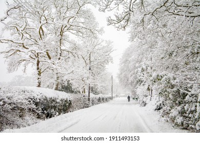 A Solitary Figure Walking On A Snow Covered Road