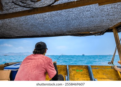 Solitary Fisherman Waiting for a Catch at Sea. Bright Blue Sea Under the Midday Sun. - Powered by Shutterstock