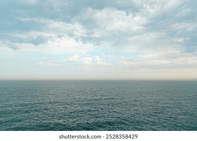 A solitary fishing boat navigates the vast, calm ocean under a pale sky. The minimalistic scene conveys solitude, tranquility, and the endless expanse of the sea. - Powered by Shutterstock