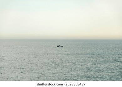 A solitary fishing boat navigates the vast, calm ocean under a pale sky. The minimalistic scene conveys solitude, tranquility, and the endless expanse of the sea. - Powered by Shutterstock