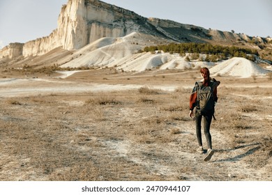 solitary hiker trekking through arid desert landscape with towering mountain peak in the distance - Powered by Shutterstock