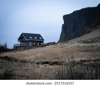 A solitary house its below a massive rock outcrop in Vik, Iceland. - Powered by Shutterstock