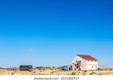 Solitary house with red roof in desert landscape with solar panels showing remote off-grid living - Powered by Shutterstock