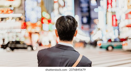 Solitary japanese corporative businessman in suit, after work, waiting on crossroad in Kabukicho, entertainment and red-light district in Shinjuku, Tokyo, Japan. - Powered by Shutterstock