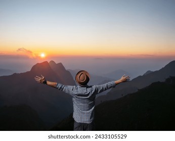 A solitary man with open arms welcomes the sunrise atop a serene mountain landscape, embracing peace and tranquility.
 - Powered by Shutterstock