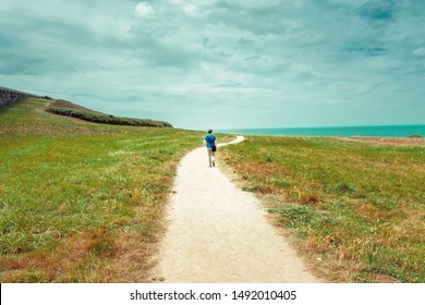 solitary man walking on a lonely dirt road to the sea