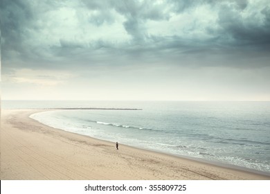 Solitary man walking on the wide beach  - Powered by Shutterstock