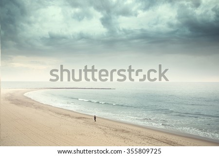 Solitary man walking on the wide beach 