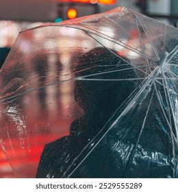 A solitary person with a transparent umbrella standing on a rainy street illuminated by vibrant city lights at night. Raindrops cascade down a transparent umbrella while a person stands beneath it,  - Powered by Shutterstock