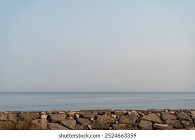 A solitary rock emerges from calm water of Ontario Lake shrouded in mist at dawn in a tranquil natural landscape - Powered by Shutterstock