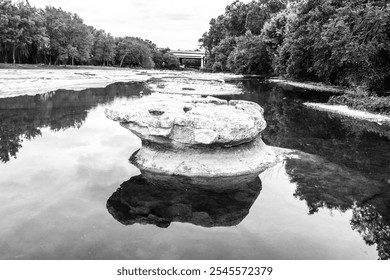 Solitary Rock Formation Reflecting in Tranquil River - Black and White Nature Photography - Powered by Shutterstock