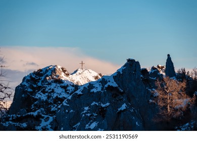 Solitary summit cross stands atop snow-covered mountain peak Mallestiger Mittagskogel, Karawanks, Carinthia, Austria. Rugged and rocky with patches of snow and exposed rock. Austrian Alps in winter - Powered by Shutterstock