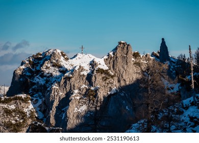 Solitary summit cross stands atop snow-covered mountain peak Mallestiger Mittagskogel, Karawanks, Carinthia, Austria. Rugged and rocky with patches of snow and exposed rock. Austrian Alps in winter - Powered by Shutterstock