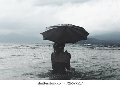 Solitary Woman With Umbrella Waiting For The Storm Into The Sea