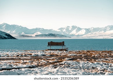 Solitude by the lake. Frozen shore, snow-capped mountains. Peaceful contemplation. - Powered by Shutterstock