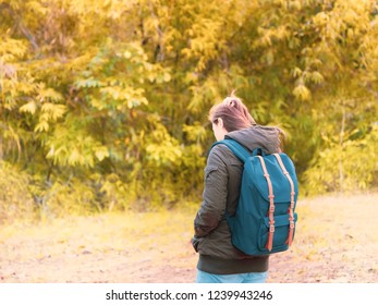 solo backpack and camping concept from backside of long hair woman in warm hoodie sweatshirt with her bag solo travel, relax, happy  and see to forest and mountain in morning after sunrise