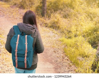 solo backpack and camping concept from backside of long hair woman in warm hoodie sweatshirt with her bag solo travel, relax, happy  and see to forest and mountain in morning after sunrise