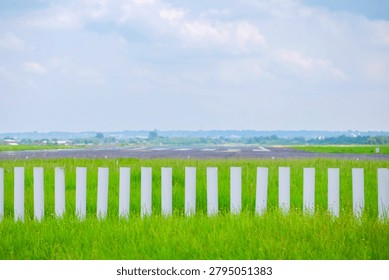 Solo, Central Java, Indonesia - December 4, 2022: A stretch of green grass with white markers on the runway at a rural airport under cloudy skies.