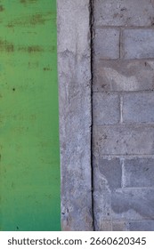 Solo, Central Java, Indonesia - July 31, 2025: Concrete Walls and Weathered Green Steel Door Panels Symmetrically Divided