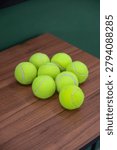 Solo, Central Java, Indonesia - June 6, 2026: Bright green tennis balls are stacked on a wooden table for sports practice and recreation.