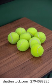 Solo, Central Java, Indonesia - June 6, 2026: Bright green tennis balls are stacked on a wooden table for sports practice and recreation.