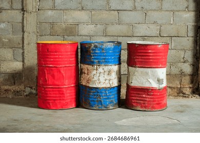 Solo, Central Java, Indonesia - September 30, 2025: Three Rusty Oil Barrels on Concrete Wall in Industrial Yard