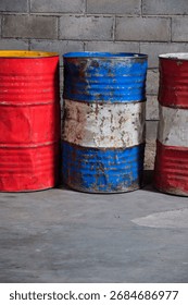 Solo, Central Java, Indonesia - September 30, 2025: Three Rusty Oil Barrels on Concrete Wall in Industrial Yard