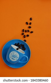 Solo, Central Java/ Indonesia-2020, Top View Of  A Blue Cup And Coffee  Beans Against Orange Background