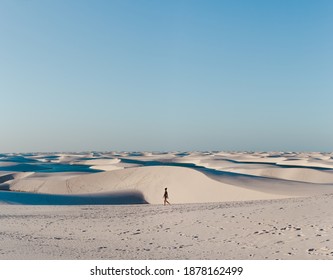 Solo female backpacker walks across the sand dunes of Lencois Maranhenses, miles and miles of sand dunes and lagoons in Maranhao, North-Eastern Brazil