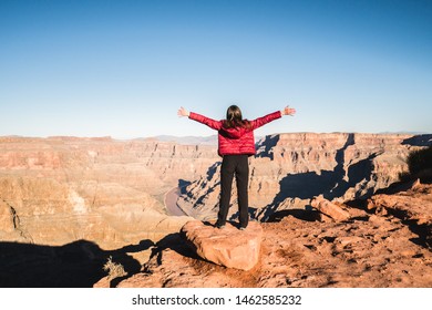 Solo girl traveler spreading her arms by the edge of a cliff, enjoying life and being inspired by the beautiful scenic view of Grand Canyon, Arizona, United States - Powered by Shutterstock