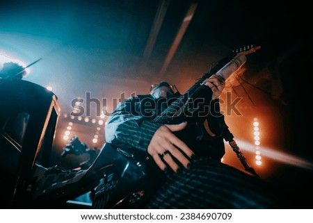 the solo guitarist on stage effectively holds the guitar. a guitarist without a face holds an electric guitar