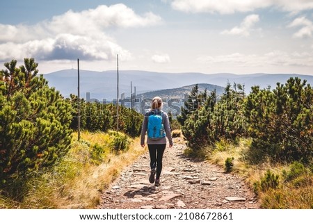 Solo hiker walking on trekking trail in mountain. Woman with backpack hiking in natural parkland Jeseniky, Czech Republic. Sports active lifestyle