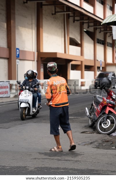 Solo,
Indonesia - February 27, 2022 : A Parking attendant is walking on
the street at Pasar Klewer in Solo (Central
Java)