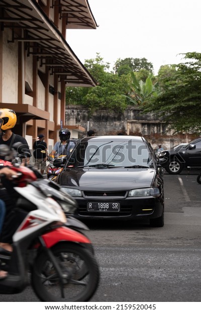 Solo,\
Indonesia - February 27, 2022 : a Mitsubishi Galant crosses the\
street at Pasar Klewer in Solo (Central\
Java)
