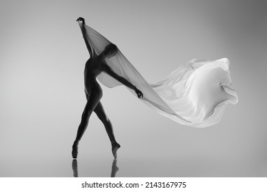 Solo Performance. Black And White Portrait Of Graceful Ballerina Dancing With Fabric, Cloth Isolated On Grey Studio Background. Grace, Art, Beauty, Contemp Dance Concept. Weightless, Flexible Actress