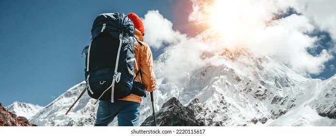 Solo tourist with travel backpack walk along high altitude mountain track. Outdoor mountains explorer traveling among snowy summit rock. Wide image - Powered by Shutterstock