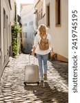 Solo travel. Woman tourist with suitcase and backpack walking on street. Traveling and vacation in european city Olomouc, Czech Republic