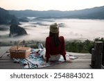 Solo traveler is relaxing on balcony surrounded by green forest and foggy mountain view in the early morning, north of Thailand. Concept of people and healthy natural lifestyle.