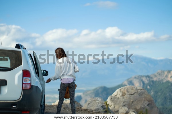 Solo traveling\
road trip. Woman closing door of car, reaching destination to\
mountains valley in Turkey