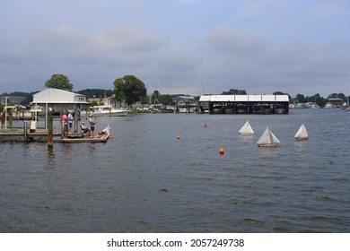 Solomons, Maryland, USA - July 11 2021: Wooden Toy Sailboats Sailing Close To The Shore.