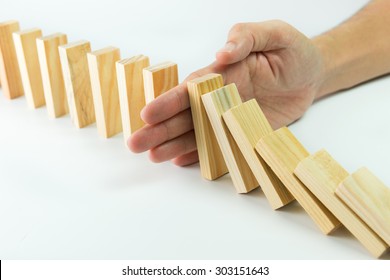 Solution concept with hand stopping wooden blocks from falling in the line of domino - Shutterstock ID 303151643
