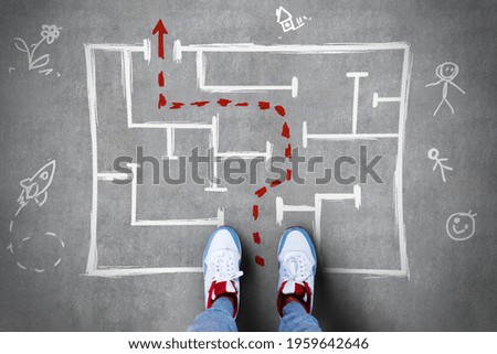 Solution concept with human feet in front of handwritten maze with red dotted line showing a way out