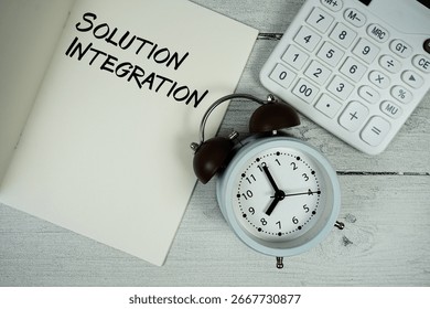 Solution Integration text on paper notebook page with alarm clock and calculator on wooden background