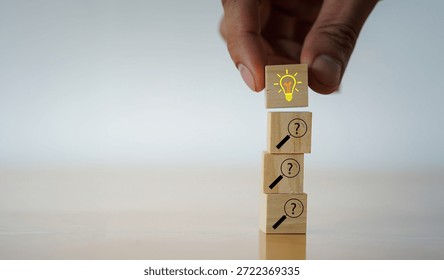 Solution, problem solving concept. Wooden blocks with a lightbulb and question mark magnifiers icons, symbolizing inquiry leading to insight and problem solving.