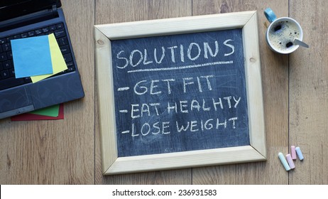 Solutions Get, Fit, Eat Healthy And Lose Weight Written On A Chalkboard At The Office