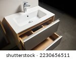 Solutions for placing things in bathroom horizontal sliding pull out drawer shelves storage in a cupboard under stoneware washbasin cabinet under sink and faucet. Modern loft flat minimalistic design.