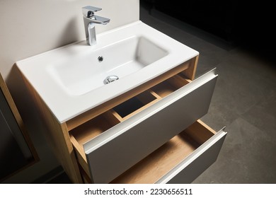 Solutions for placing things in bathroom horizontal sliding pull out drawer shelves storage in a cupboard under stoneware washbasin cabinet under sink and faucet. Modern loft flat minimalistic design.