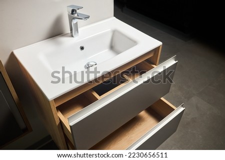 Solutions for placing things in bathroom horizontal sliding pull out drawer shelves storage in a cupboard under stoneware washbasin cabinet under sink and faucet. Modern loft flat minimalistic design.
